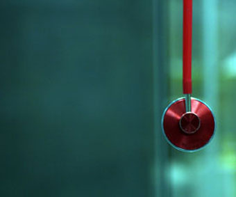closeup of red stethoscope against blurred blue-green background