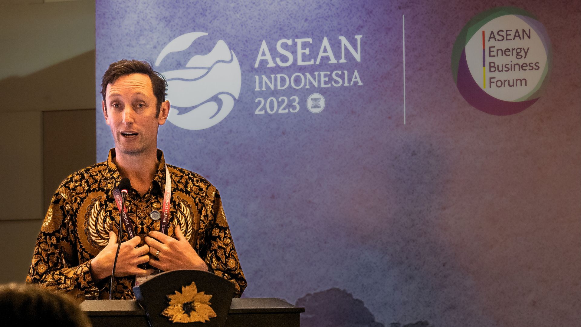 Andrew Hudson, CEO of Centre for Policy Development, in a batik shirt stands at a podium giving a speech. The background behind him reads ASEAN Indonesia 2023.